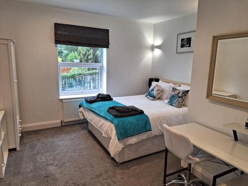 a bedroom with a bed and a desk and a window at Spacious, modern first floor flat near beach and ferry in East Cowes