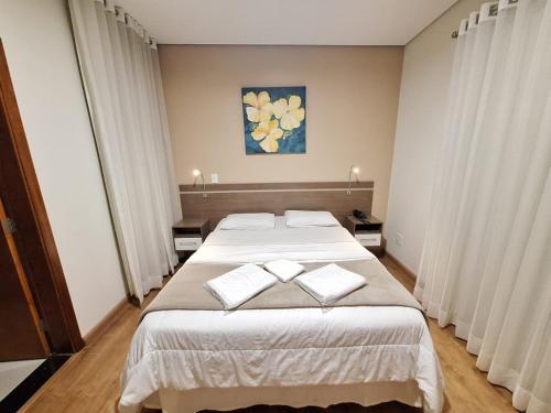a bedroom with a large bed with two white pillows at Hotel Itapema in Valinhos