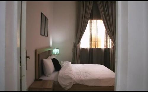 a bedroom with a white bed and a window at Blissful Lodgings in Jos