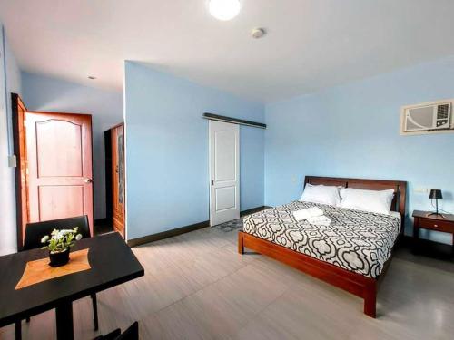 ein Schlafzimmer mit einem Bett und einem Tisch in einem Zimmer in der Unterkunft Villa Tomasa Panglao Golf & Hotel in Bolod