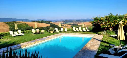 a swimming pool in a yard with chairs and umbrellas at Podere Cunina in Buonconvento