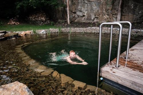 a person swimming in a pool of water at Apartmány NONE in Branná