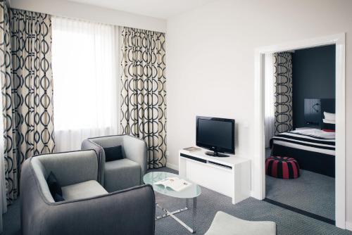 a living room with a chair and a television at Vienna House by Wyndham Andel's Berlin in Berlin