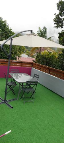a table and chair under an umbrella on a balcony at Chez Claudia in Salazie