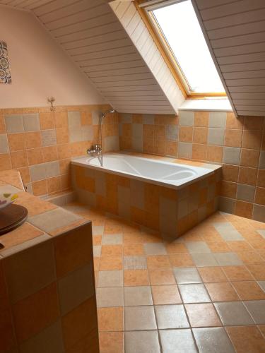 eine große Badewanne in einem Zimmer mit Dachfenster in der Unterkunft M&D Wellness in Kozármisleny