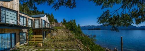 a house on the shore of a body of water at Correntoso TownHouses in Villa La Angostura