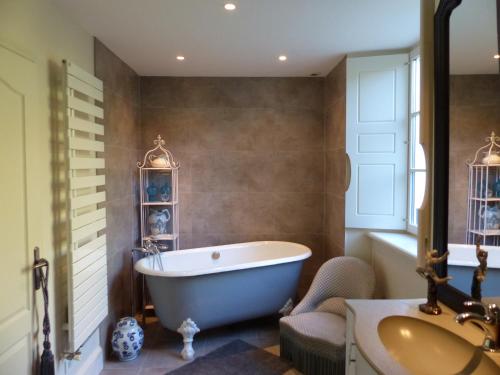 a bathroom with a white tub and a sink at La Feuillaie in Saint-Ay