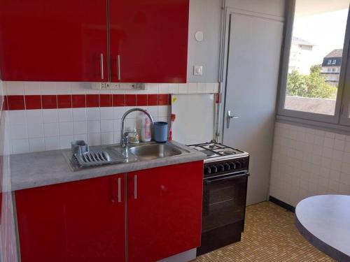 - une cuisine avec des placards rouges, un évier et une cuisinière dans l'établissement Vue sur la Basilique 'St 'Rémi, à Reims