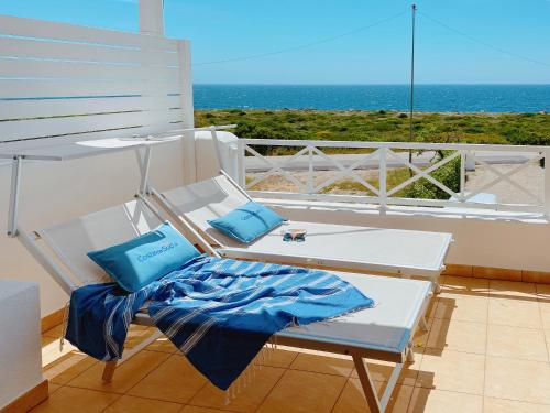 a white chair with two blue pillows on a balcony at Residence Salento Fronte Mare in Torre San Giovanni Ugento