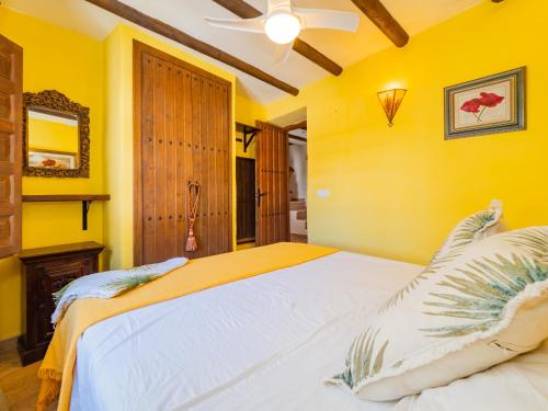 a bedroom with a large bed with yellow walls at Cubo's Casa Mas Axarquia BBQ Roof Terrace in Sedella