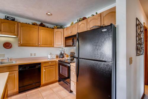a kitchen with wooden cabinets and a black refrigerator at The Plaza Condominiums by Crested Butte Mountain Resort in Mount Crested Butte