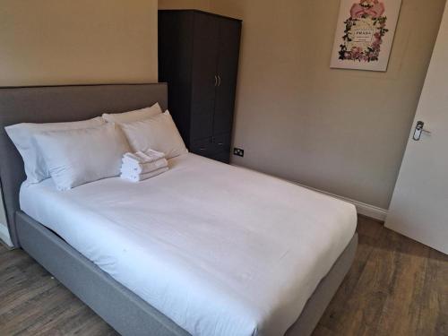 uma cama com lençóis brancos e um bicho de peluche em Westcliff - On -Sea em Southend-on-Sea