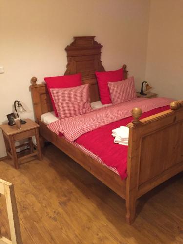 a bedroom with a wooden bed with red pillows at POD SVATOU ANNOU - penzion a řízkovna in Horní Maršov