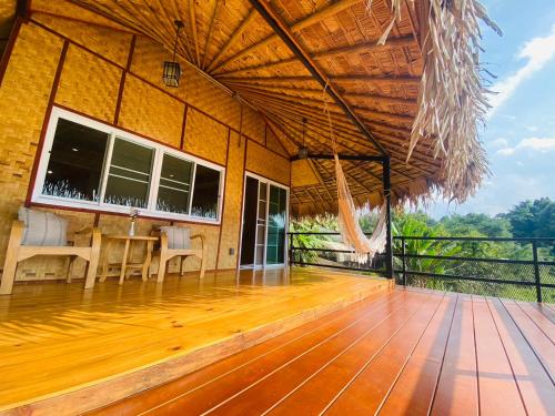 a house with a deck with a table and chairs at Daelorpu 1 แดลอปู in Ban Yang