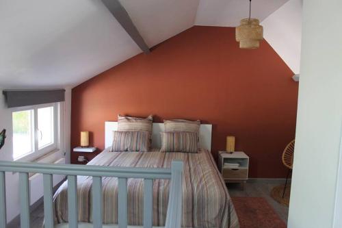 - une chambre dotée d'un lit avec un mur orange dans l'établissement Maison rénovée Atoué loc, à Fresnay-sur-Sarthe