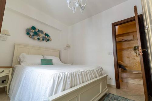 a bedroom with a bed with white sheets and a chandelier at The Cyclops Retreat - Seaview in Aci Castello