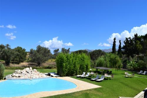 uma piscina num quintal com cadeiras e árvores em Simatos αpARTments & Studios em Lassi