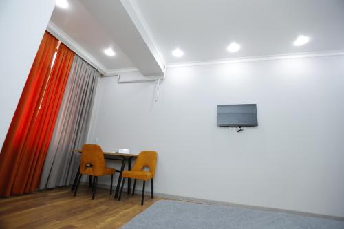 Habitación con mesa, 2 sillas y TV. en Apart Hotel Bishkek, en Bishkek