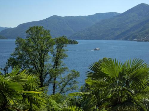 a boat in a large body of water with mountains at Hotel Arancio in Ascona