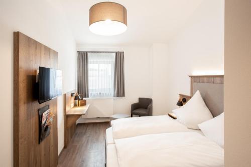 a hotel room with two beds and a television at Landgasthof Maier in Vilsbiburg