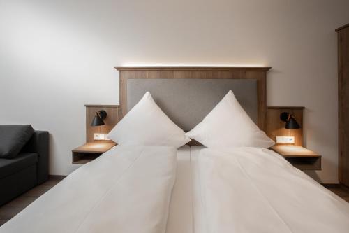 a bedroom with a bed with white sheets and pillows at Landgasthof Maier in Vilsbiburg