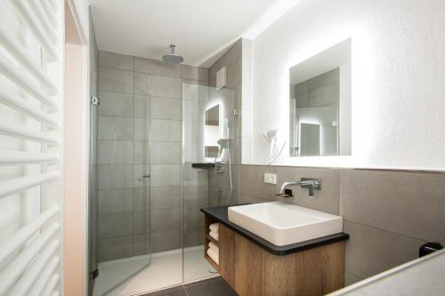 a white bathroom with a sink and a shower at Landgasthof Maier in Vilsbiburg
