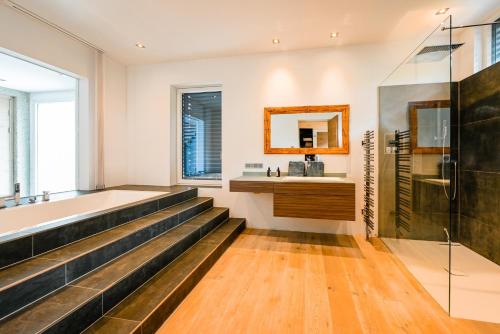 a bathroom with a bath tub and a sink at Alpin Chalet Arte in Söll