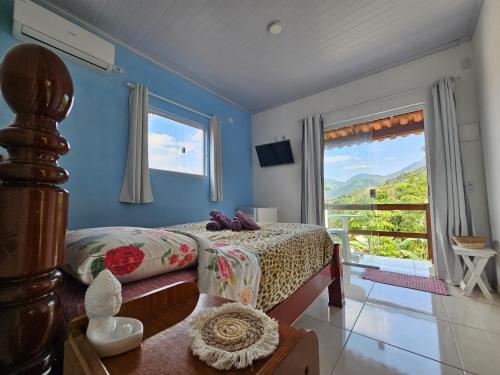 ein Schlafzimmer mit einem Bett und einem großen Fenster in der Unterkunft Pousada Encontro das Águas in Trindade