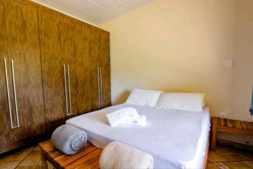 um quarto com uma cama branca e armários de madeira em Casinha aconchegante em meio a natureza em Rio Acima
