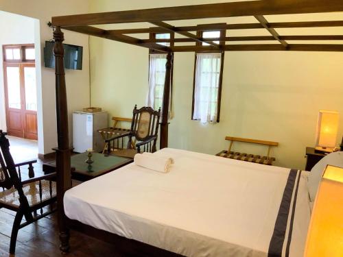 a bedroom with a bed and some chairs at Headman House Antique Villa - Ahangama in Ahangama