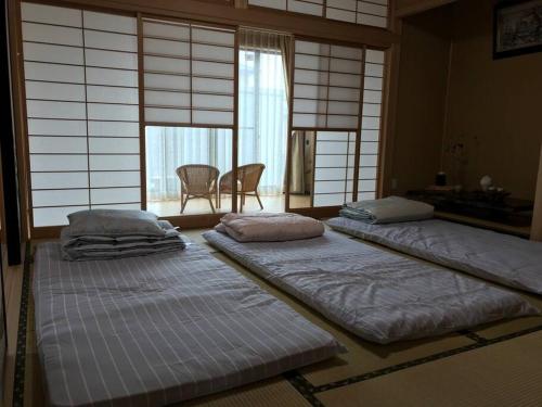 a room with three beds in a room with windows at SOZENSYA 駅、高速インターに近い新築日本家屋です。庭が広く、BBQも楽しめます。 in Kikugawa