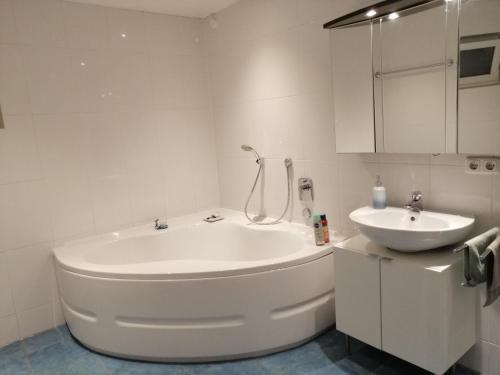 een witte badkamer met een bad en een wastafel bij Ferienwohnung Borger in Sauerlach