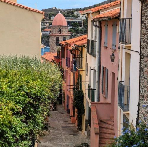 an alley in a town with a church in the distance at Petite maison quartier hist in Collioure