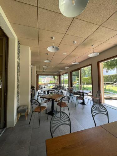 a dining room with tables and chairs and windows at Hotel La Torre in Castiglione dʼIntelvi