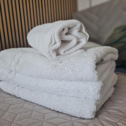 a stack of white towels sitting on a bed at Green De Lux Apartament Dziwnów in Dziwnów