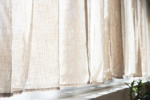 a window with white curtains and a plant at Gèa Athenian Suites in Athens