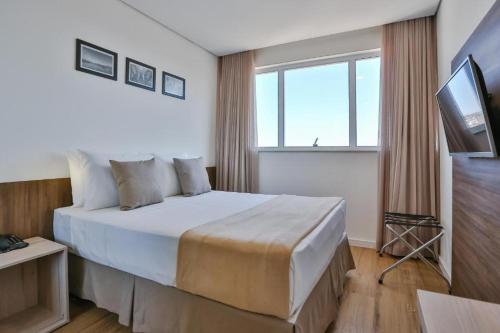 um quarto de hotel com uma cama e uma televisão em Nobile Residences London Anapolis em Anápolis