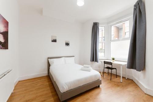 ein weißes Schlafzimmer mit einem Bett und einem Schreibtisch in der Unterkunft Great Rooms in Plaistow in London