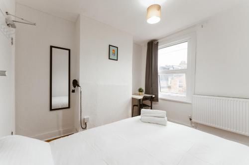 a white bedroom with a large bed and a window at Great Rooms in Plaistow in London