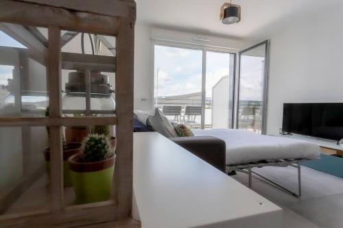 Una sala de estar con una cama y un televisor. en Le Nid des Romains - T2 neuf - Balcon - vue, en Annecy