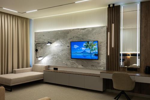 uma sala de estar com uma televisão na parede em Amsterdam Hotel Aktobe em Aqtöbe