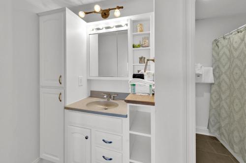 Un baño blanco con lavabo y espejo. en Aegean 104 - Updated Aegean Gulf Front Property, en Destin
