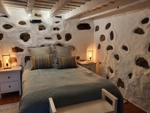 1 dormitorio con 1 cama y pared de piedra en Casa Rural LOS PINARES El Juncal de TEJEDA, en Tejeda