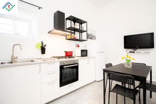 eine Küche mit weißen Schränken und einem schwarzen Tisch in der Unterkunft LeS House - Apartment 1 in Pisa