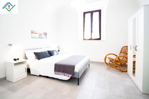 a white bedroom with a bed and a chair at LeS House - Apartment 1 in Pisa