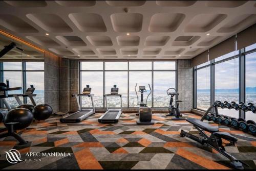 a gym with exercise equipment in a building with windows at Apec Mandala HaDoFinn in Tuy Hoa