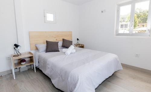 Un dormitorio blanco con una cama grande con un osito de peluche. en Casa Luna Rural Con Piscina y Jardín, en Ourense