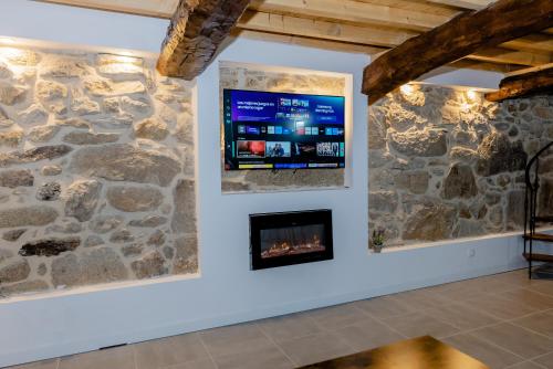 a fireplace in a stone wall with a flat screen tv at Casa Luna Rural Con Piscina y Jardín in Ourense