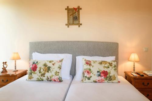 a bedroom with a bed with two pillows and a cross on the wall at Villa Armeni by CorfuEscapes in Corfu