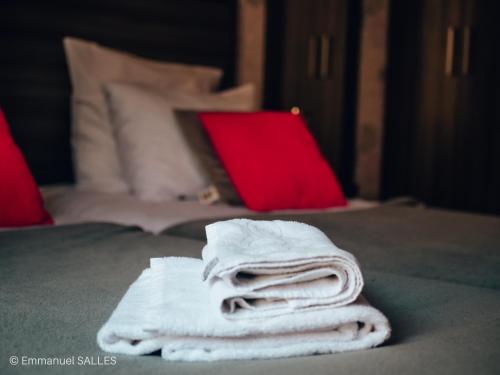una pila de toallas en una cama con un ordenador portátil rojo en Hôtel Le Saint Patrice, en Bayeux